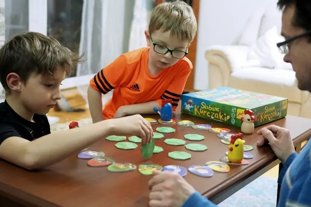 dzieci grające w grę planszową edukacyjną w domu
