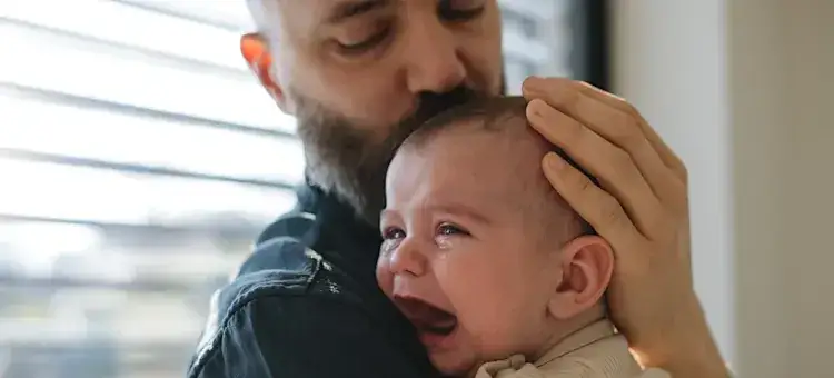zaniepokojony rodzic przytulający płaczące niemowlę